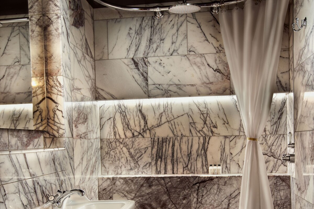 A bathroom with a marble wall, a sink, and a bathtub.
