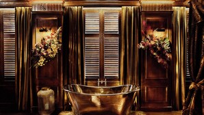 A luxurious bathroom with a freestanding bathtub, wooden paneling, and floral arrangements. - House of Gods - Glasgow (Glasgow)