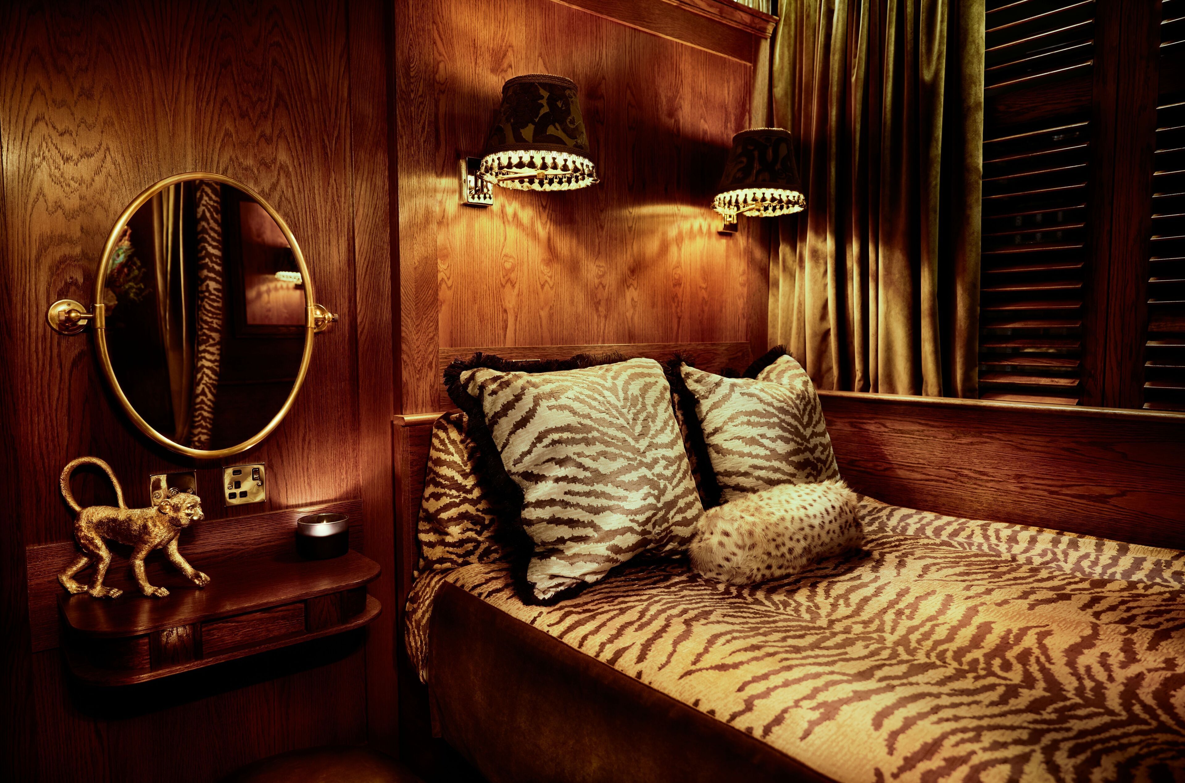 A wooden room with a bed, a round mirror, and two wall-mounted lamps.