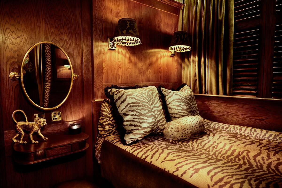 A wooden room with a bed, a round mirror, and two wall-mounted lamps.