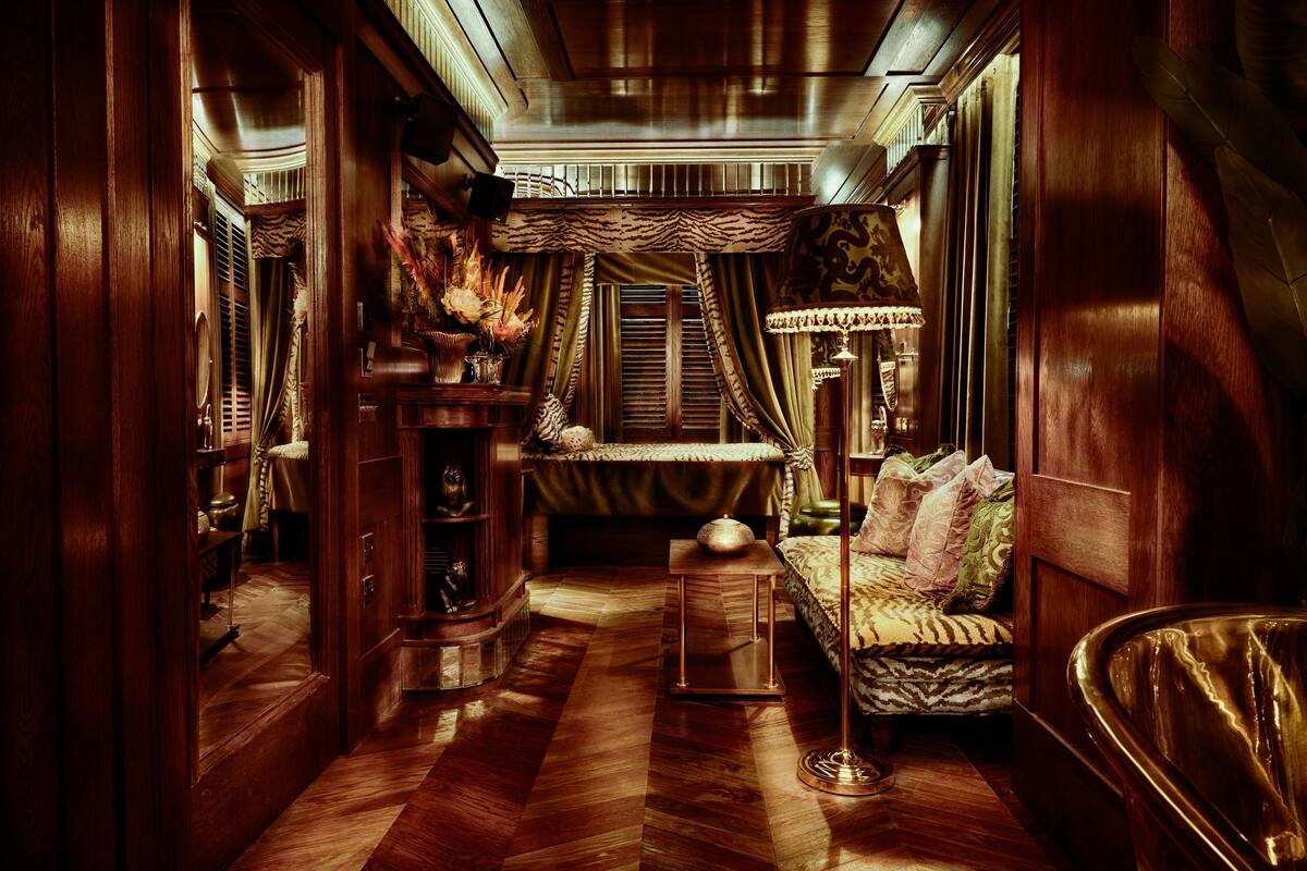 A luxurious room with a wooden floor, a bed with patterned bedding, a side table, and a lamp.