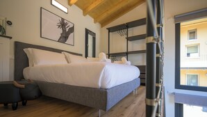 A modern bedroom with a large bed, wooden flooring, and a view of the outside balcony. - Open space on two floors in detached cottage in ancient medieval courtyard (Solarolo)