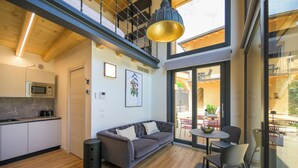 A modern interior with a kitchen, a gray sofa, a dining area, and a staircase leading to an upper level. - Open space on two floors in detached cottage in ancient medieval courtyard (Solarolo)
