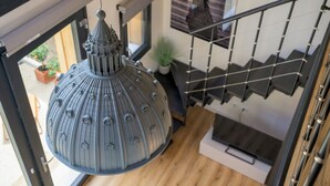A modern interior with a hanging lamp, a staircase, and a potted plant. - Open space on two floors in detached cottage in ancient medieval courtyard (Solarolo)