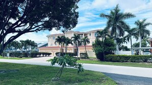 A residential area with a large house, palm trees, and a well-maintained lawn. - Cozy 2-bedroom apartment in gorgeous Downtown Cape Coral with, Pool, AC, WiFi (Cape Coral)