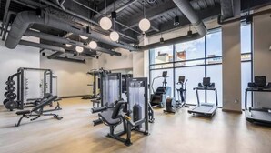 Ein Fitnessstudio mit unterschiedlichen Trainingsgeräten, großen Fenstern und einem modernen Industriedesign.