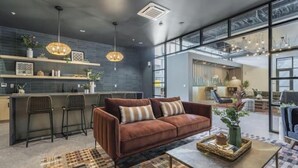 Ein modernes Interieur mit einer braunen Ledersofa, einem gemusterten Teppich und einer Küchenzeile mit Barhocker.