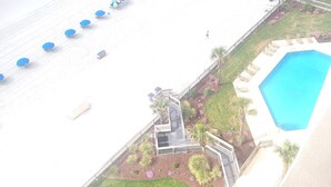Une plage avec des parasols, une piscine et un escalier menant à une terrasse.