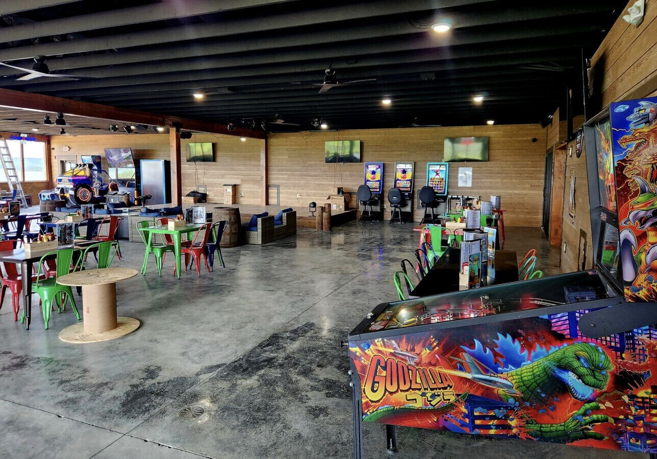 A spacious indoor area with multiple gaming machines, green and red chairs, and tables.