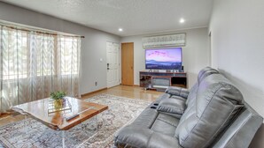 Una sala de estar con sofá, mesa de centro, televisión y una puerta.