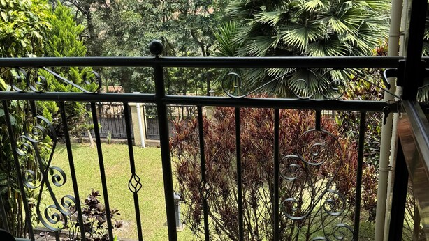 A balcony with a view of a garden, including various plants and a lawn. - Dafrican BnB  (Kigali)
