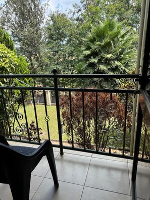 A balcony with a view of a garden, including various plants and a lawn. - Dafrican BnB  (Kigali)