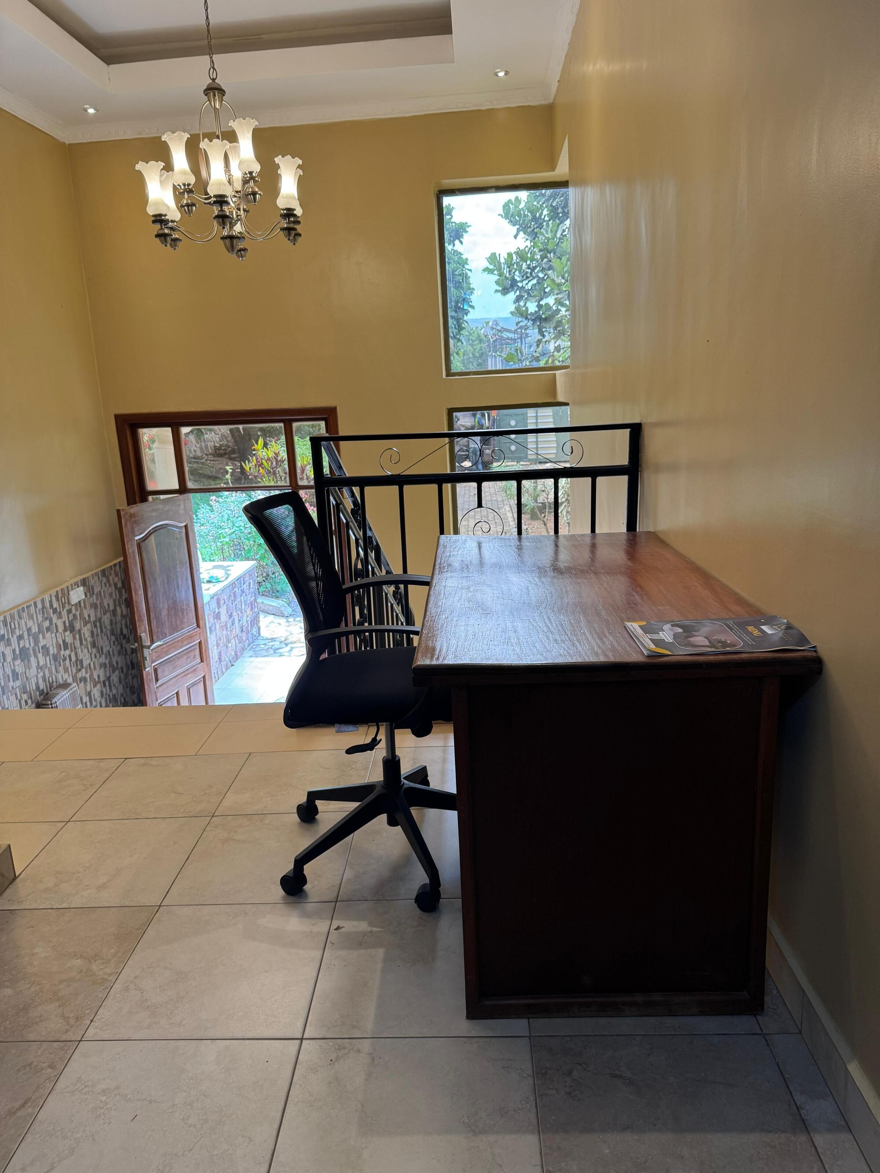 Un salón de conferencias con una mesa de madera, una silla de oficina negra y una araña.