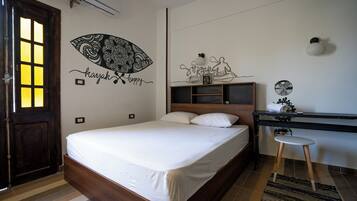 Een slaapkamer met een houten bed, een bureau met stoel, een muur met decoratieve kunst en een deur met raam.