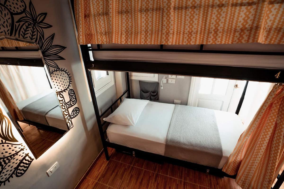 Habitación con literas, un perchero y una pared con motivos de frutas y hojas.