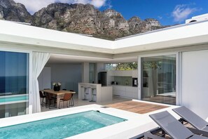 Un espacio exterior moderno con piscina, zona de comedor y cocina.