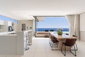 A modern kitchen with a dining area overlooking the sea.