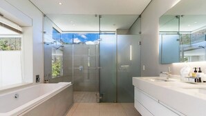 A modern bathroom with a glass-enclosed shower, a large bathtub, and a vanity with a mirror. - Aquatic Penthouse - Coastal Luxury & Rooftop Views (Cape Town)