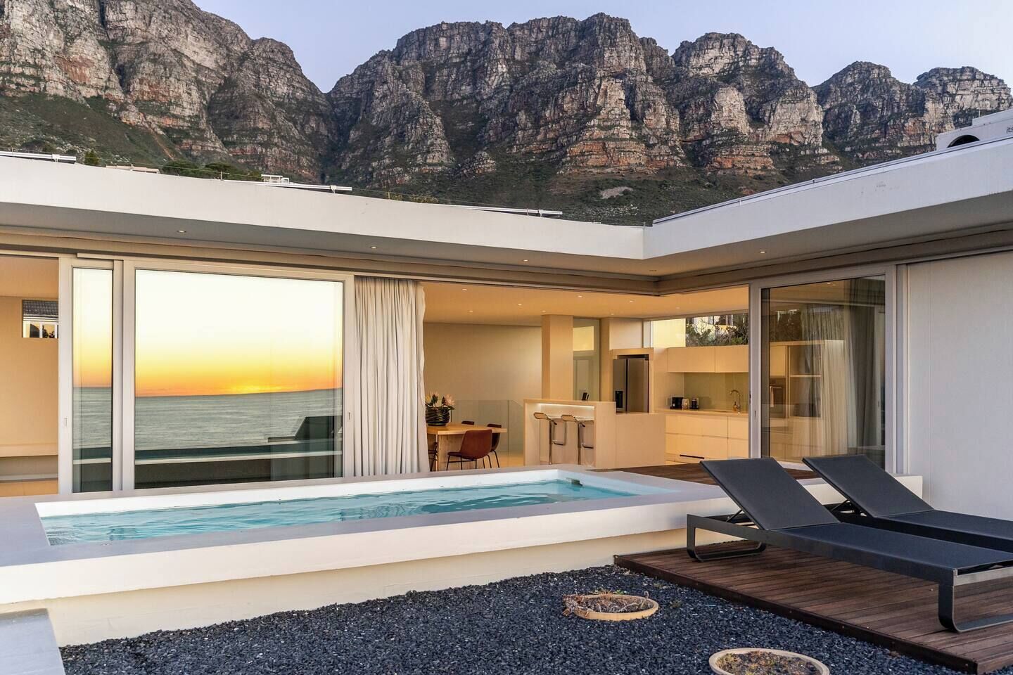 A modern outdoor pool area with a view of the ocean and mountains.