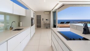 Une cuisine moderne avec vue sur l’océan, un four encastré et une grande fenêtre.
