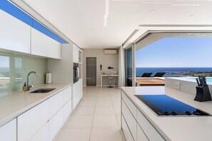 Una cocina moderna con vista al océano, horno empotrado y un amplio ventanal.