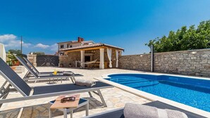 A swimming pool with lounge chairs and a stone wall. - Villa Leonardelli in Galizana (Galizana)