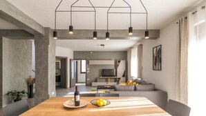 A modern dining area with a wooden table, chairs, and a wine bottle. - Villa Leonardelli in Galizana (Galizana)