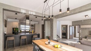 A modern kitchen with a central island, bar stools, and pendant lighting. - Villa Leonardelli in Galizana (Galizana)
