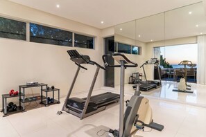 A home gym with treadmills, weights, and a mirrored wall.