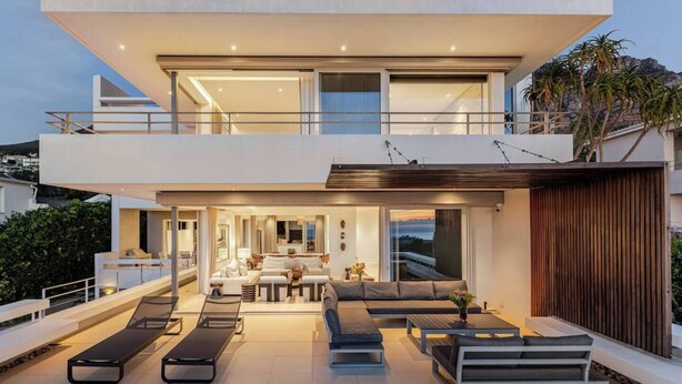 Uma casa moderna de dois andares com varanda, área de estar externa e vista para a paisagem.