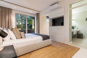 A modern bedroom with a large bed, a flat-screen TV, and a sliding door leading to a balcony.