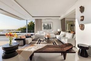 A modern living room with a large window, a sofa set, a coffee table, and decorative items.