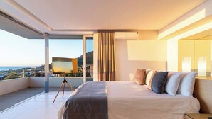 Ein modernes Schlafzimmer mit einem großen Bett, Blick auf die Stadt und einem Balkon.