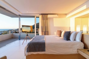 A modern bedroom with a large bed, a view of the city, and a balcony.
