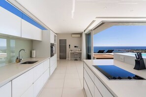 A modern kitchen with a view of the ocean, a built-in oven, and a large window.