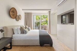 A modern bedroom with a bed, a TV, and a view of the outdoors.