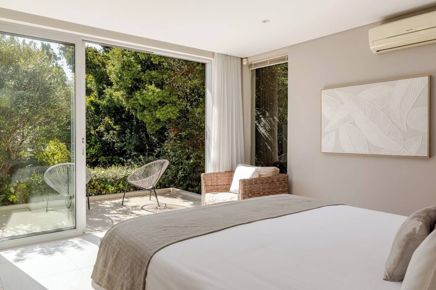 Une chambre avec un grand lit, une chaise et une vue sur la verdure.