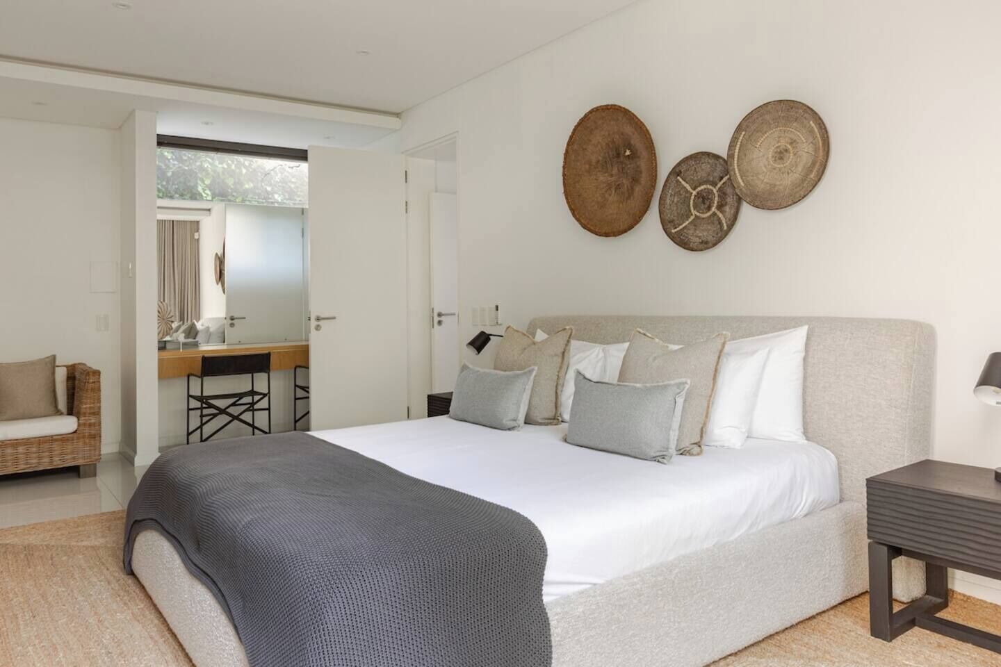 A modern bedroom with a large bed, a desk, and a chair.