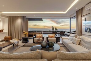 Een moderne woonkamer met een groot raam dat uitkijkt op een prachtig uitzicht, ingericht met banken, een salontafel en decoratieve objecten.
