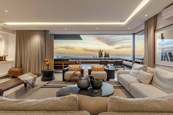 Un salon moderne doté d’une grande fenêtre offrant une vue panoramique, et aménagé avec des canapés, une table basse et des objets décoratifs.