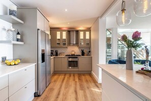 A modern kitchen with a central island, stainless steel appliances, and a view of a dining area.