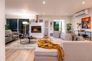 A modern living room with a fireplace, sofas, a coffee table, and a large window.