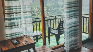 A balcony with a view of a mountainous landscape, a wooden table, and a chair. - Ella Rock Mystery Hotel (Ella, Sri Lanka)