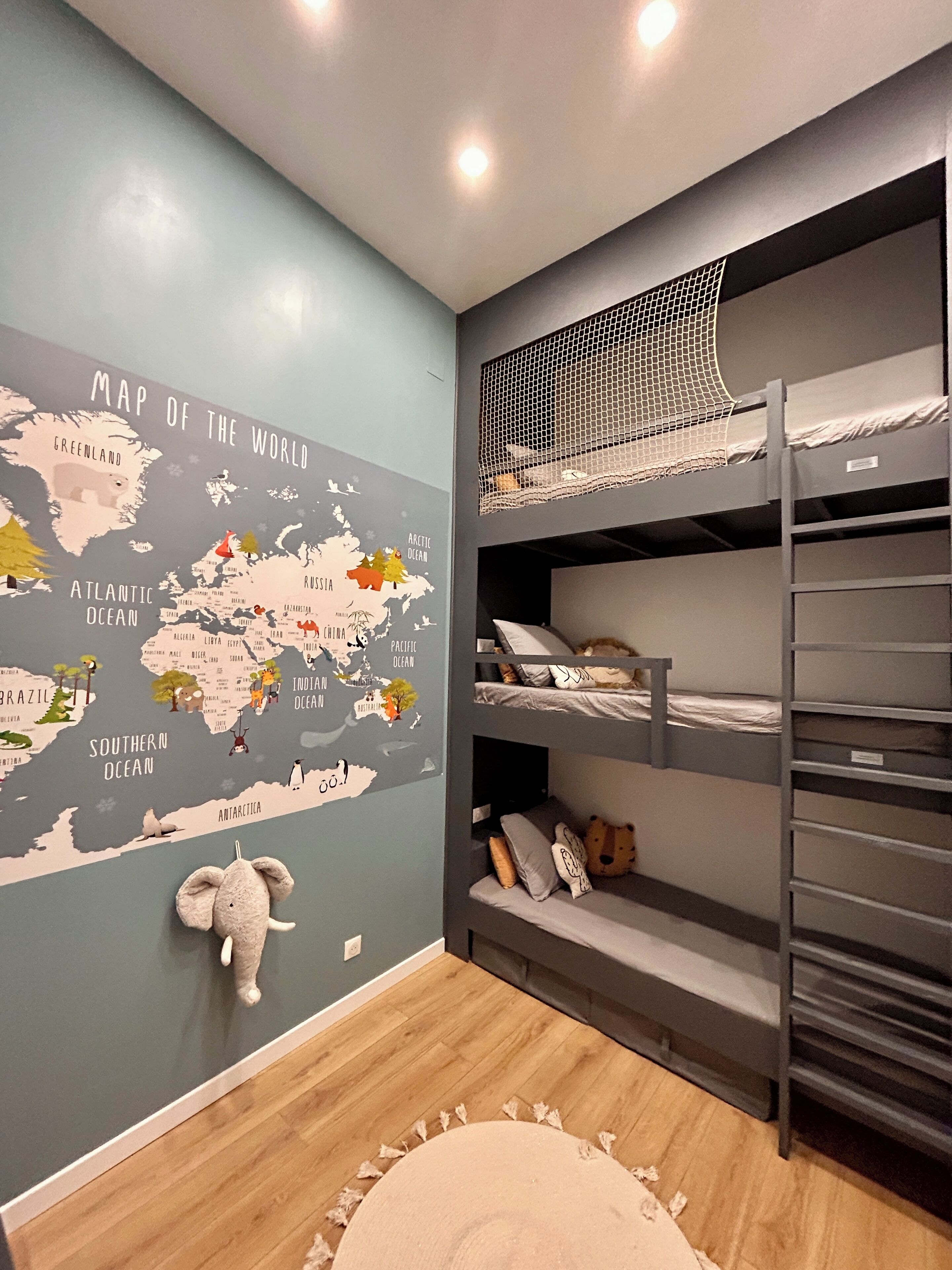 Habitación infantil con un mapa del mundo, literas y un elefante de peluche.