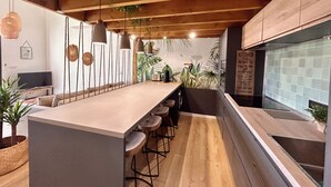 Una cocina moderna con una isla central, taburetes de bar, lámparas colgantes y un salpicadero con un letrero de cocina.