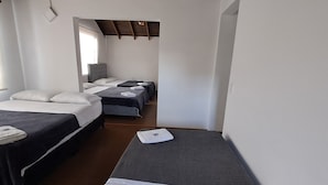 A room with three single beds, wooden beams on the ceiling, and white walls. - Fortaleza Diosa Chia (Chia)