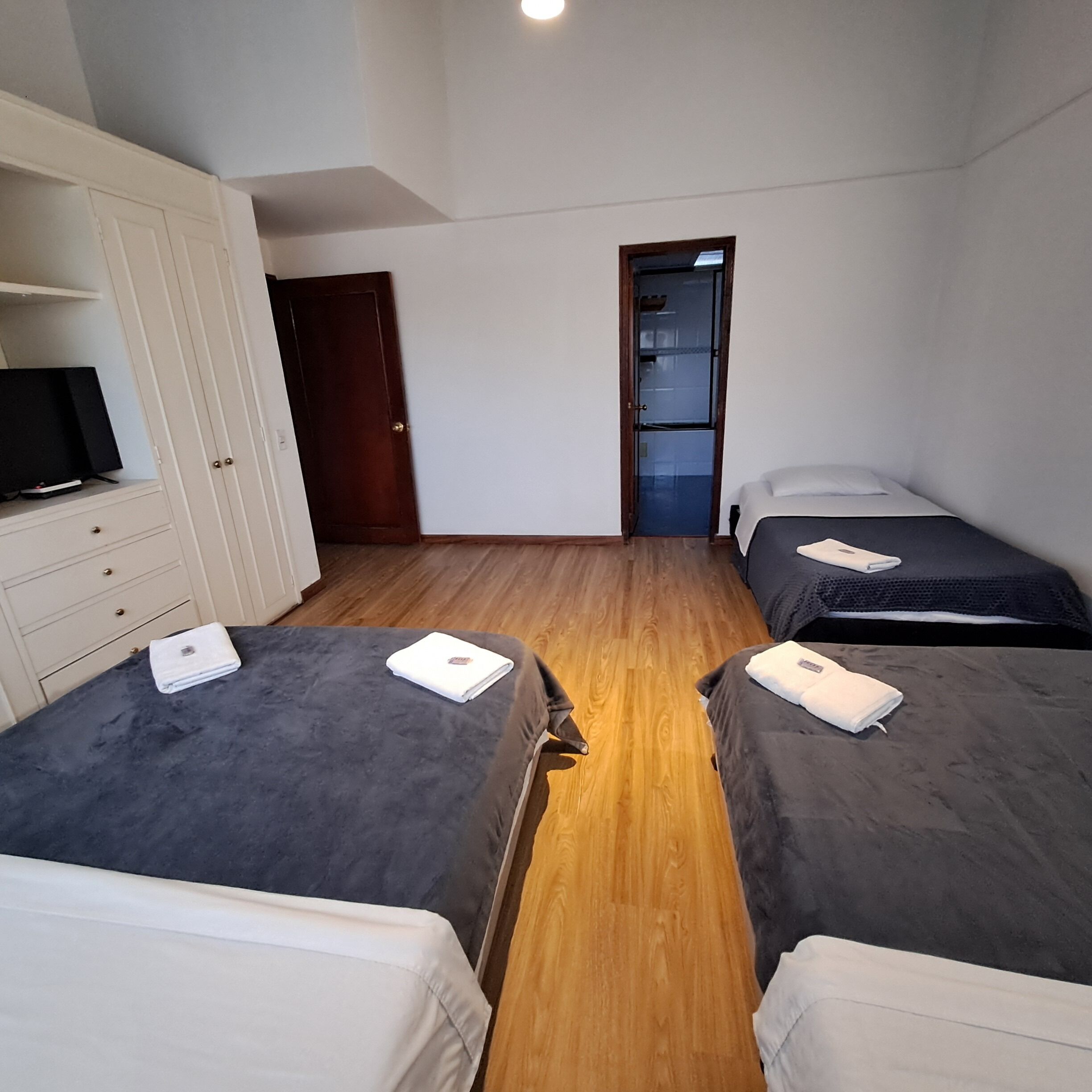 A small, clean room with two beds, a TV, and a wardrobe.