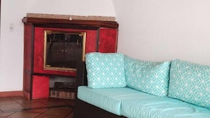 A living room with a sofa, a fireplace, and tiled flooring. - Fortaleza Diosa Chia (Chia)