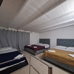 Una habitación de hotel con dos camas, un ventanal grande con cortinas y un techo alto.