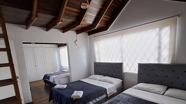 A hotel room with two beds, a wardrobe, and a window with blinds. - Fortaleza Diosa Chia (Chia)
